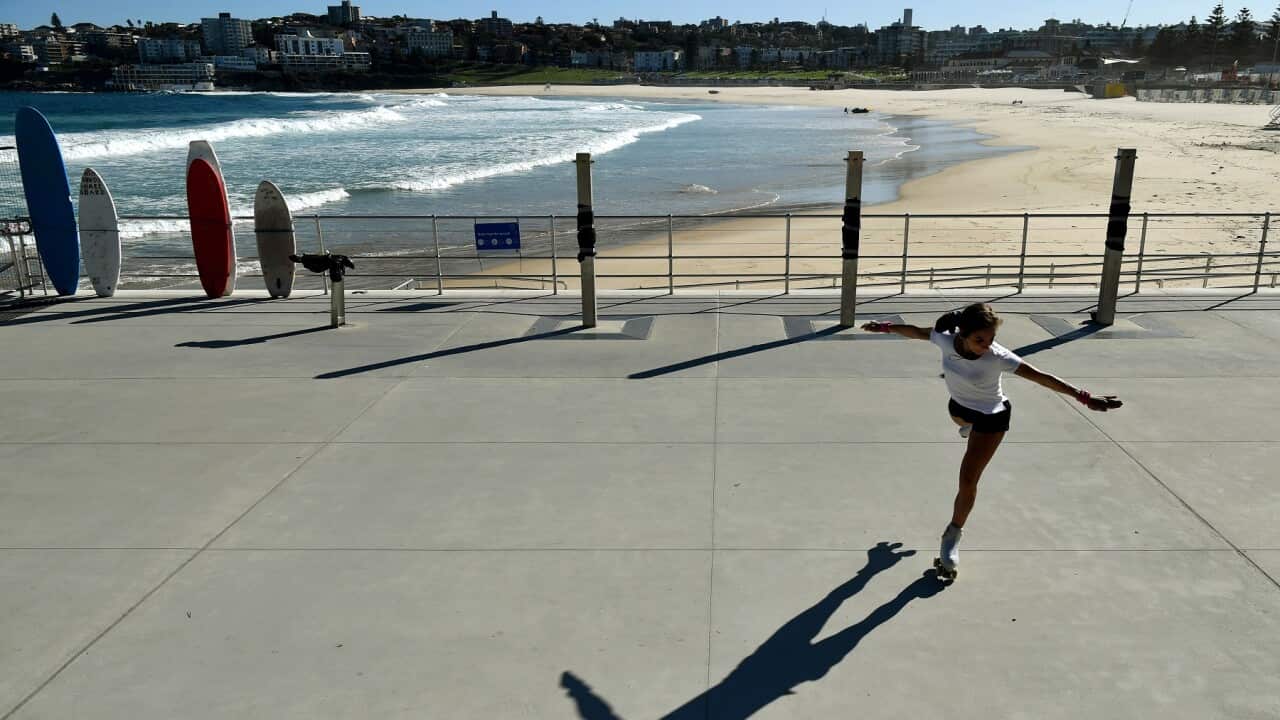 A woman roller skates in front of a closed Bondi Beach in Sydney, Sunday, April 12, 2020. (AAP Image/Joel Carrett) NO ARCHIVING
