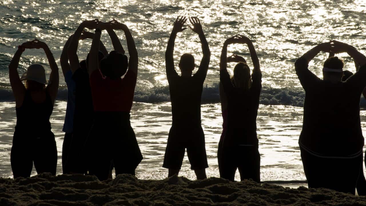 People face the ocean as they stretch during a Tai Chi exercise session at Currumbin Beach on the Gold Coast, Monday, Sep. 16, 2013. (AAP Image/Dave Hunt) NO ARCHIVING
