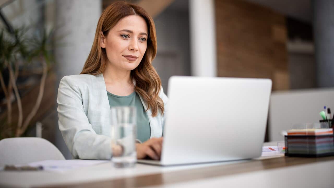 A woman sitting at a desk using a laptop.