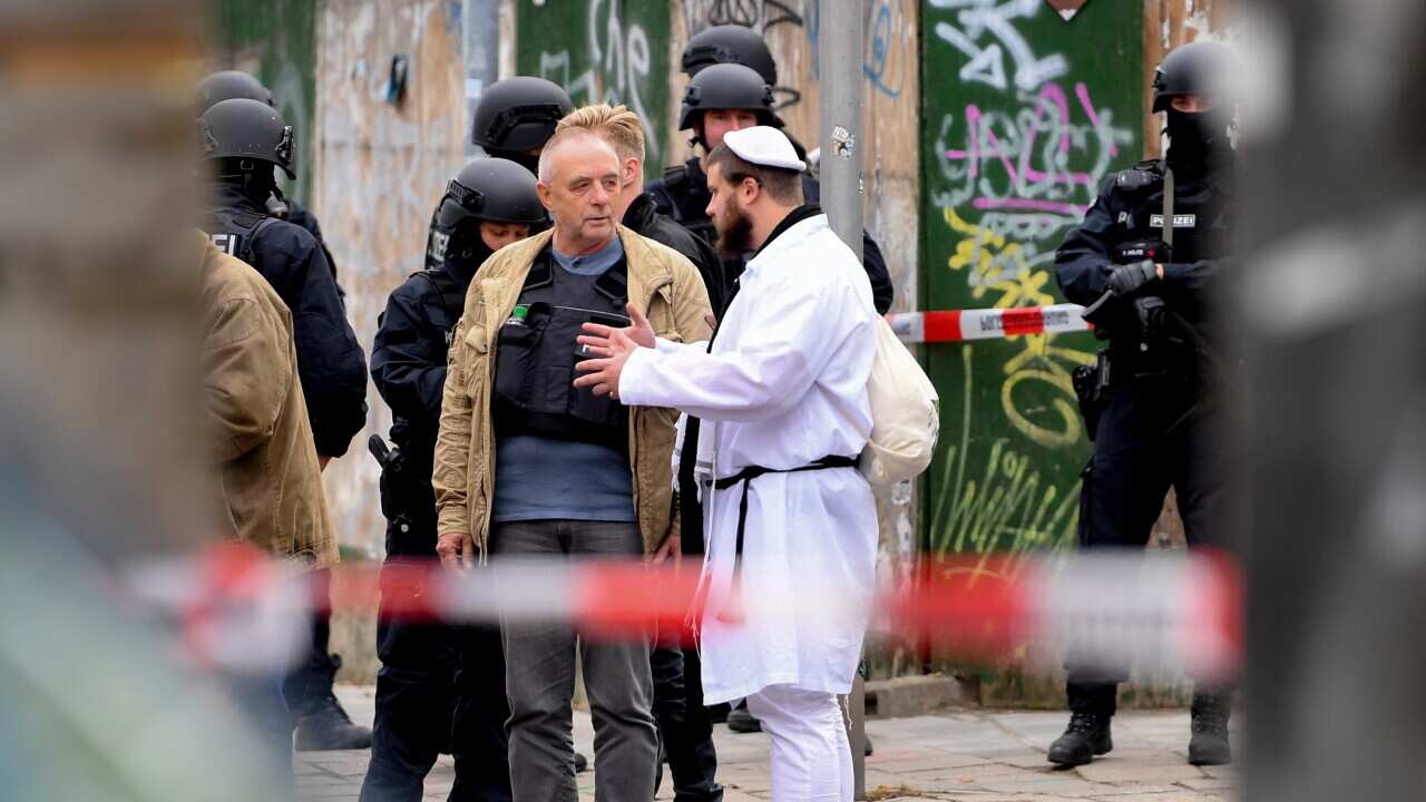 A synagogue visitor talks to police after a shooting at a synagogue in Halle, Germany, 09 October 2019.