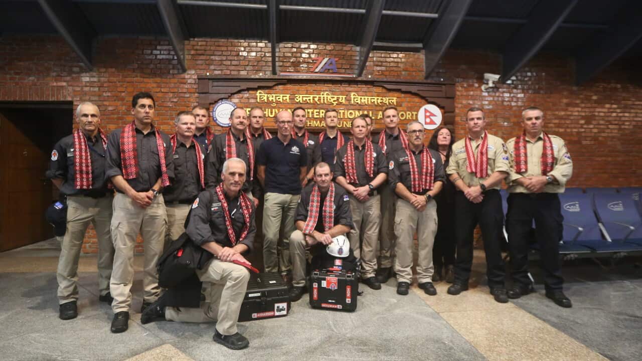 Group of emergency response personnel posing for a photo inside an airport terminal, standing beneath signs for Tribhuvan International Airport and wearing patterned scarves.