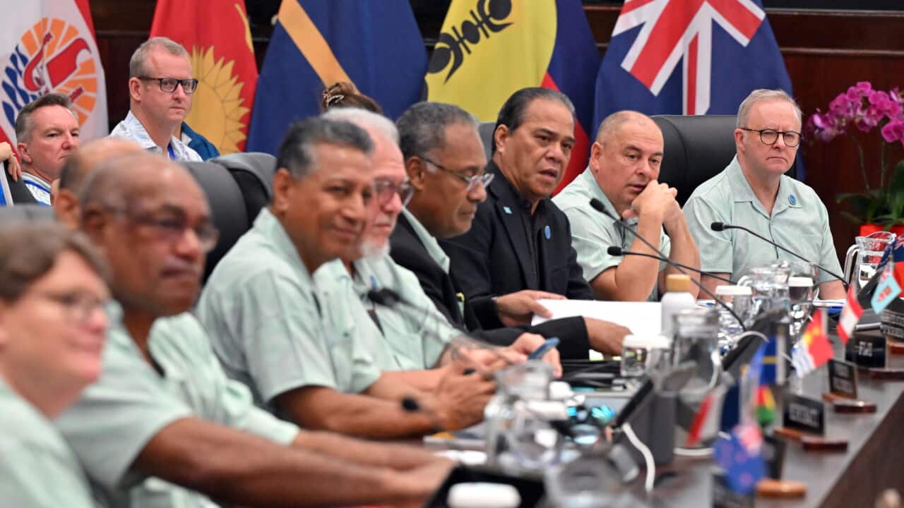 Leaders of various Pacific Island nations seated at a long table, with microphones, drinks and documents in front of them. Several national flags are behind them.