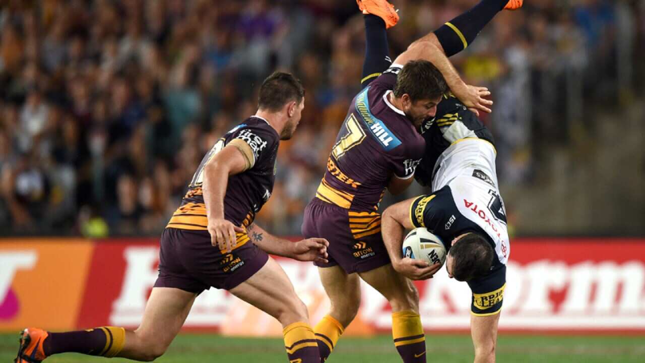 Brisbane halfback Ben Hunt (C) tackles North Queensland's Kane Linnett