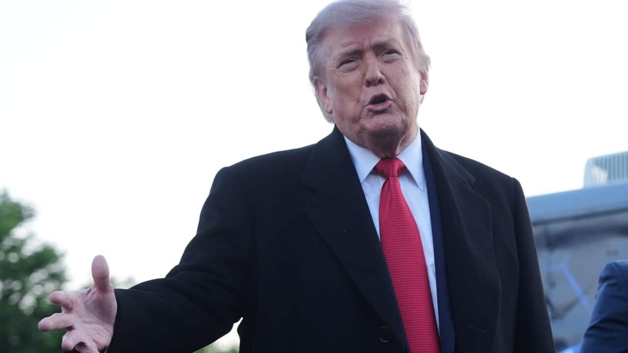 Donald Trump outside the White House wearing a black coat, red tie and white shirt