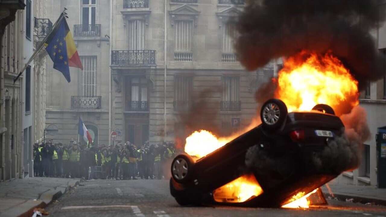 A car burns while demonstrators watch on in Paris.