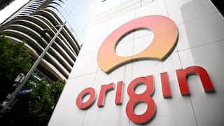 A large orange logo affixed to the side of a beige city building.