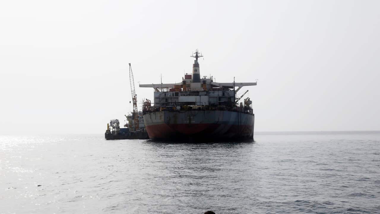 An oil tanker approaching, illuminated by bright sunlight.