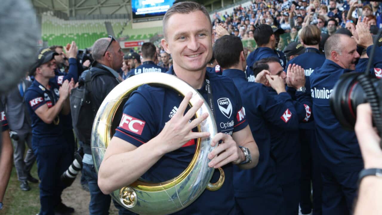 Melbourne Victory player Besart Berisha carries the A-League grand final trophy at AAMI stadium in Melbourne