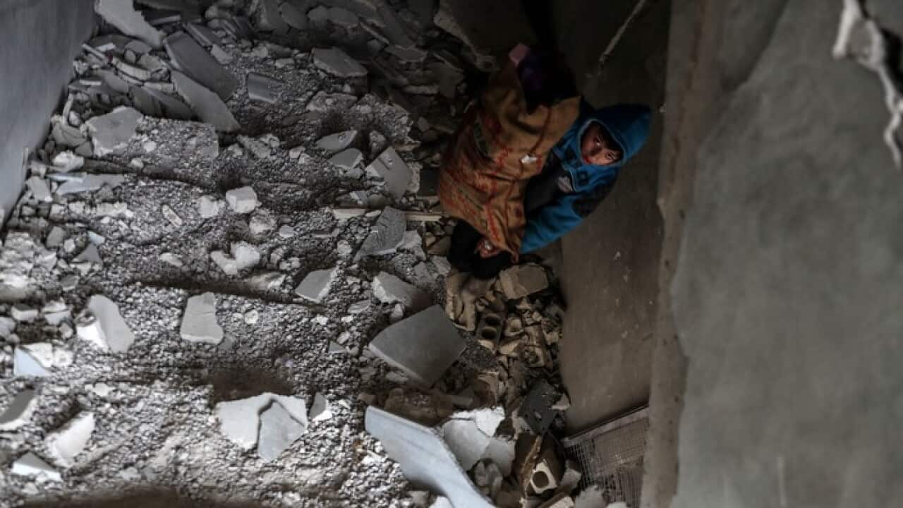 A boy looks through the rubble of a building damaged in airstrikes in Douma, Eastern Ghouta, Syria