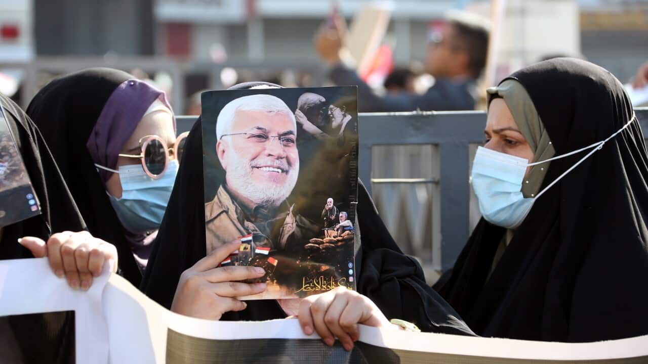 Iraqi Shiite women hold pictures of Qasem Soleimani and Abu Mahdi al-Muhandis