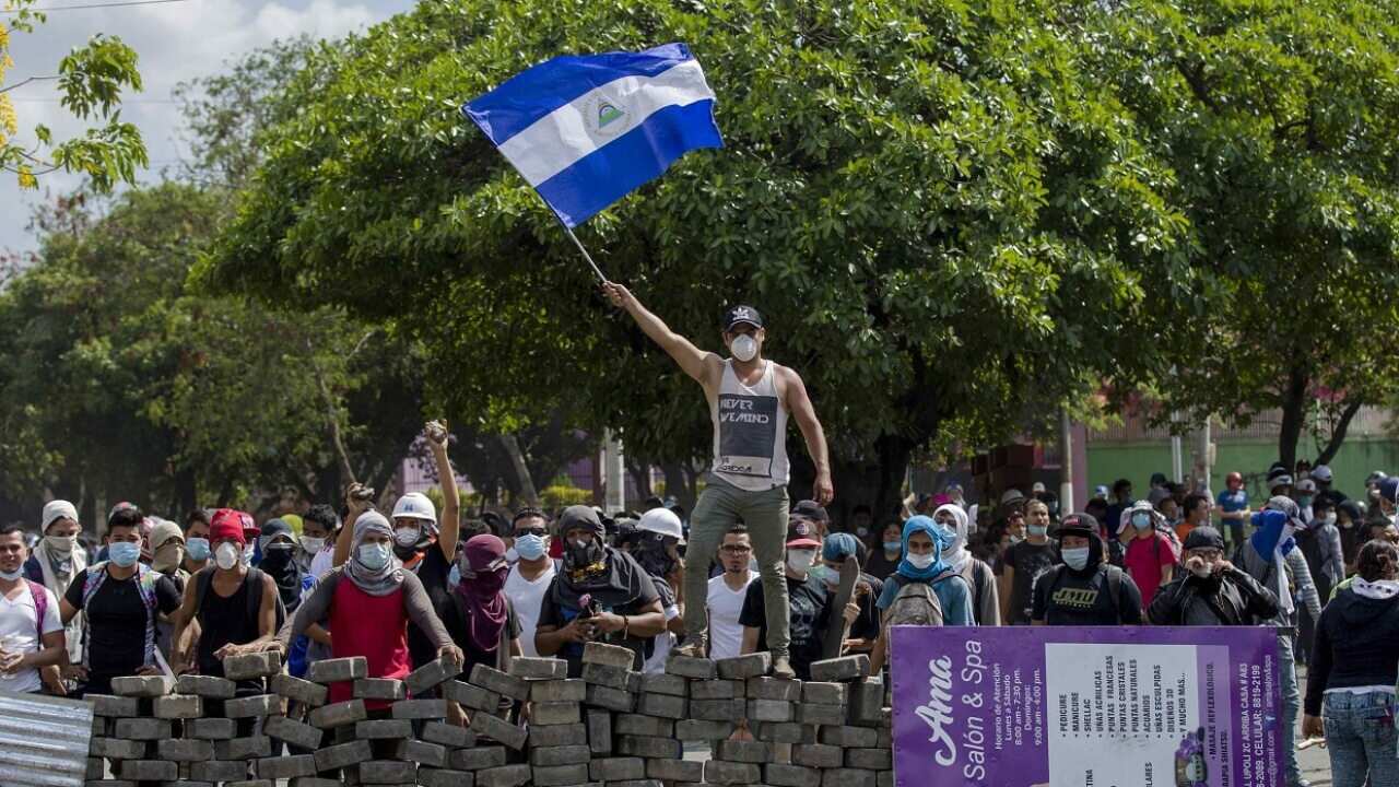 A young man raises a Nicaraguan national flag on a cobblestone barricade in Managua, Nicaragua, on April 21.