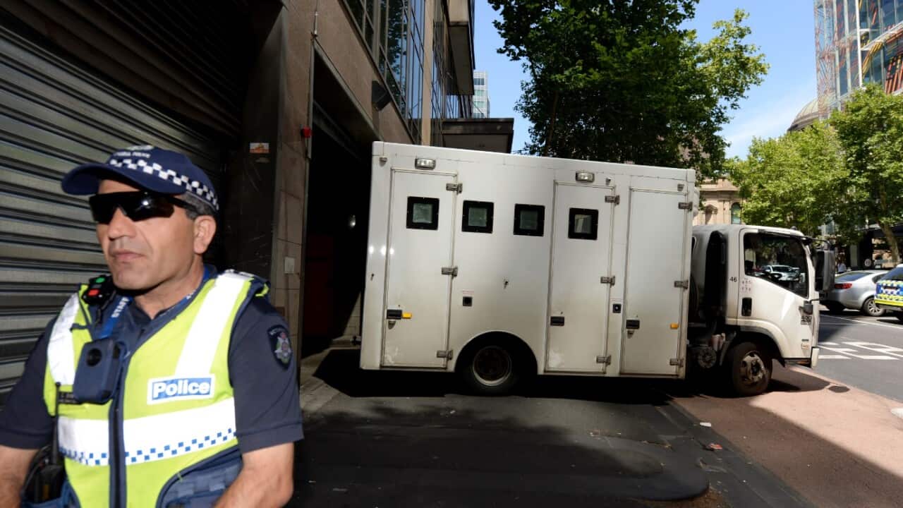  Police officers block the street and footpath as police vehicles enter and leave the Magistrates Court in Melbourne, Friday, Dec. 23, 2016. 