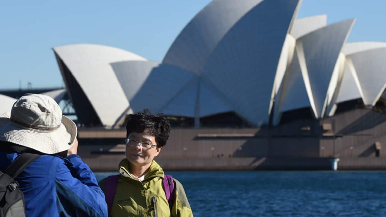 A Chinese tourists poses for a photograph on Sydney Harbour