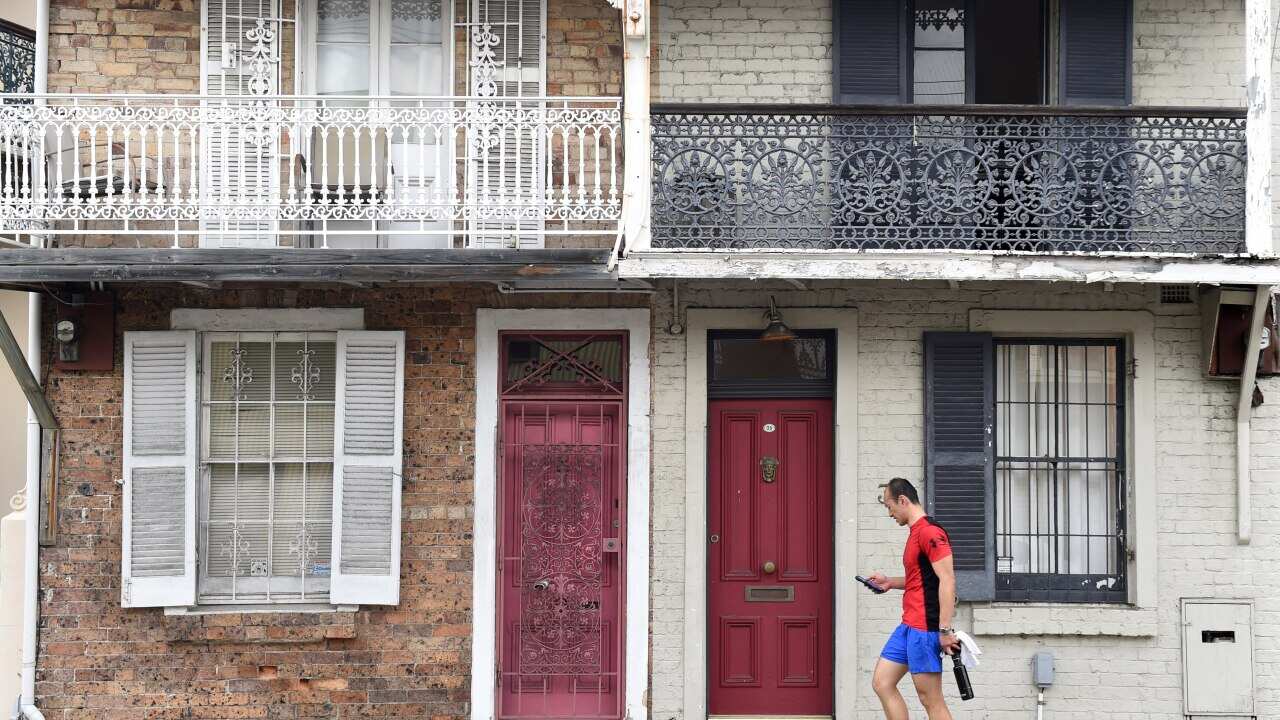 A man walks past some residential houses in Sydney.