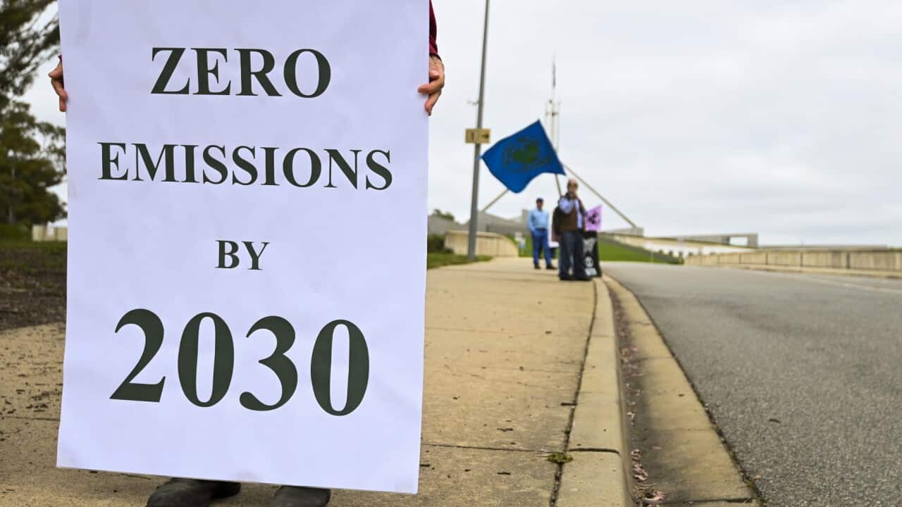 People hold banners as they participate in a climate protest outside Parliament