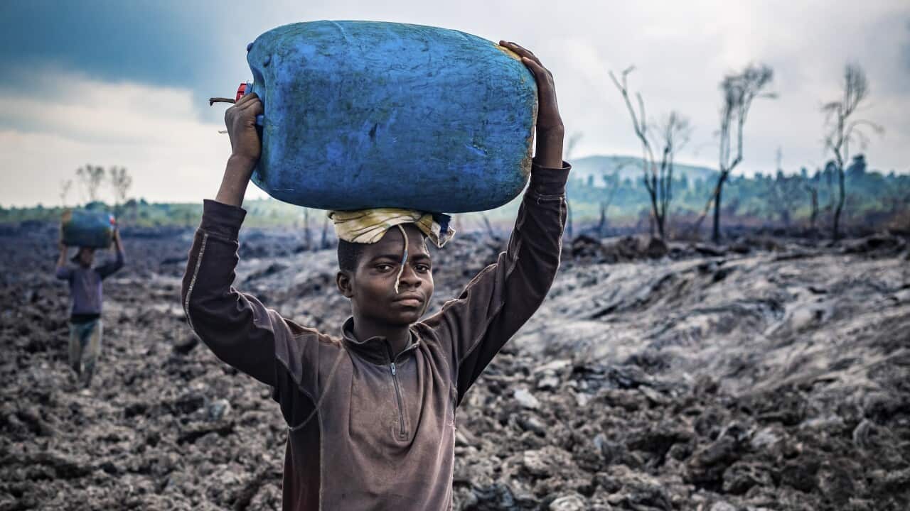 A Congolese man carries a drum as he is evacuated across cooled lava in the aftermath of Mount Nyiragongo volcano eruption.