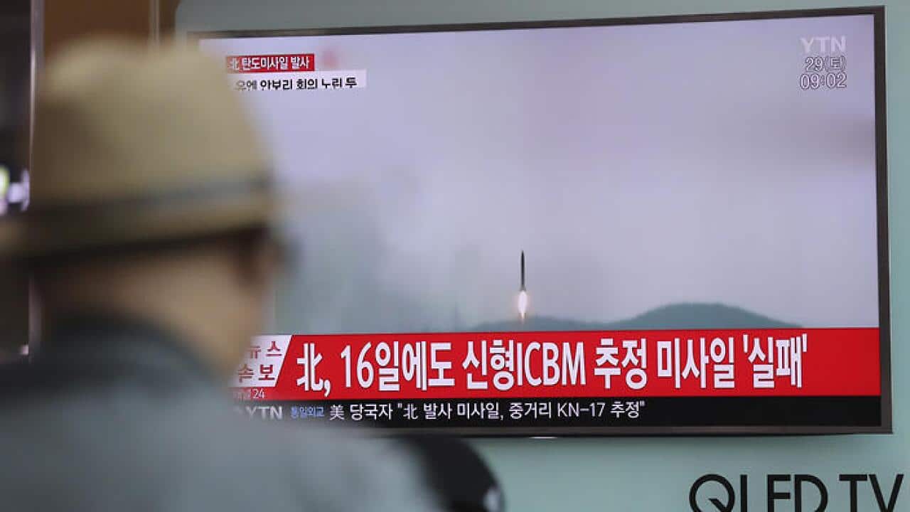 A man watches a TV news program reporting about North Korea's missile firing with a file footage, at Seoul Train Station in Seoul, South Korea