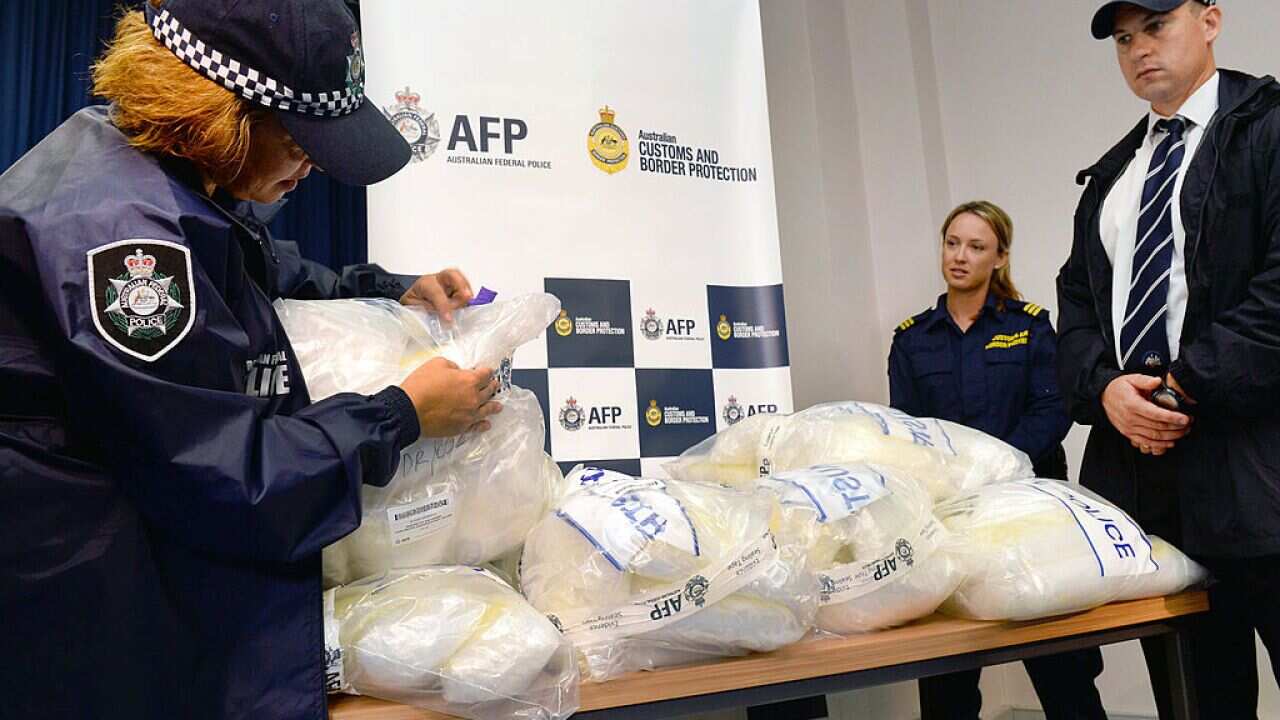 An Australian Federal Police officer inspects seized methamphetamine