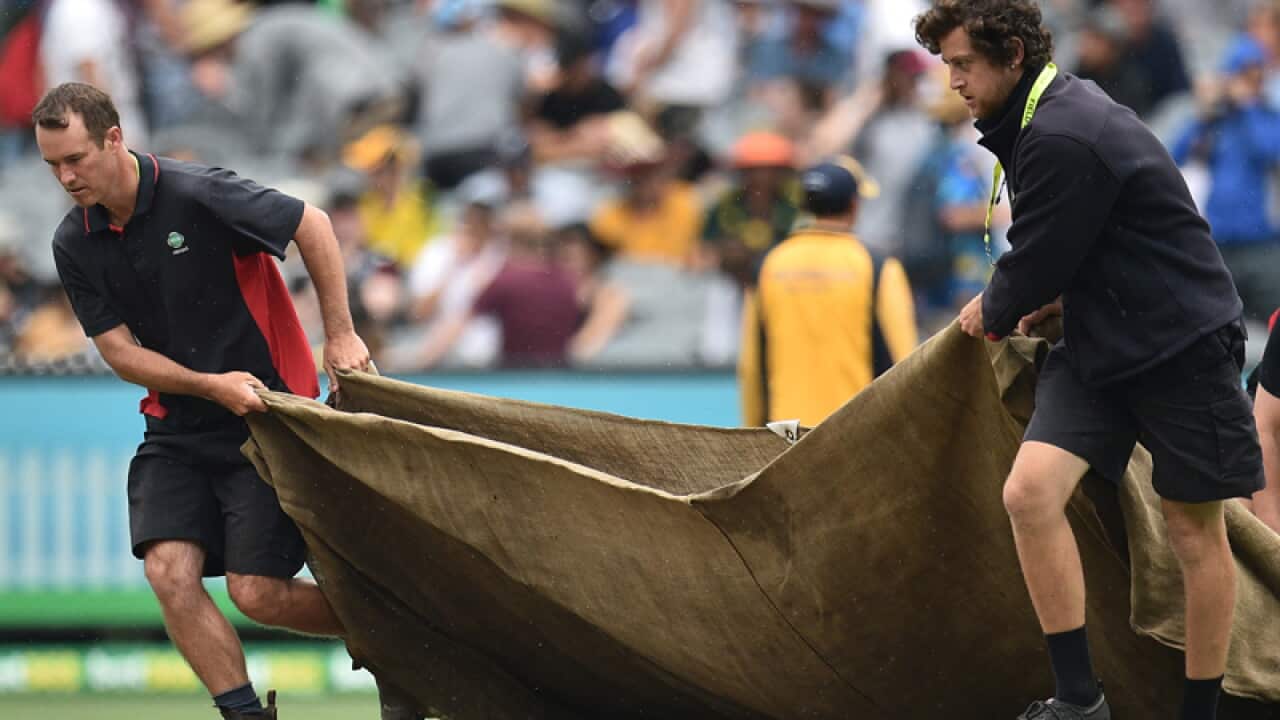 Groundsmen unfurl the covers as rain begins to fall