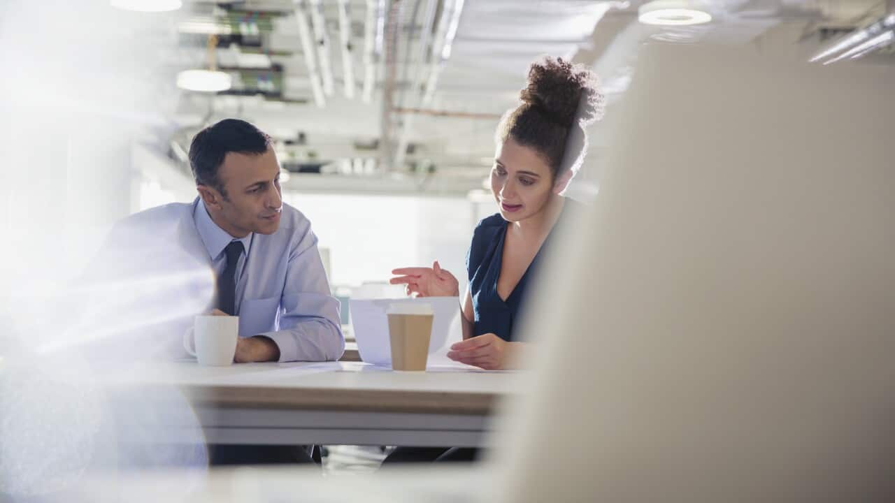 Businessman and businesswoman discussing paperwork in office meeting