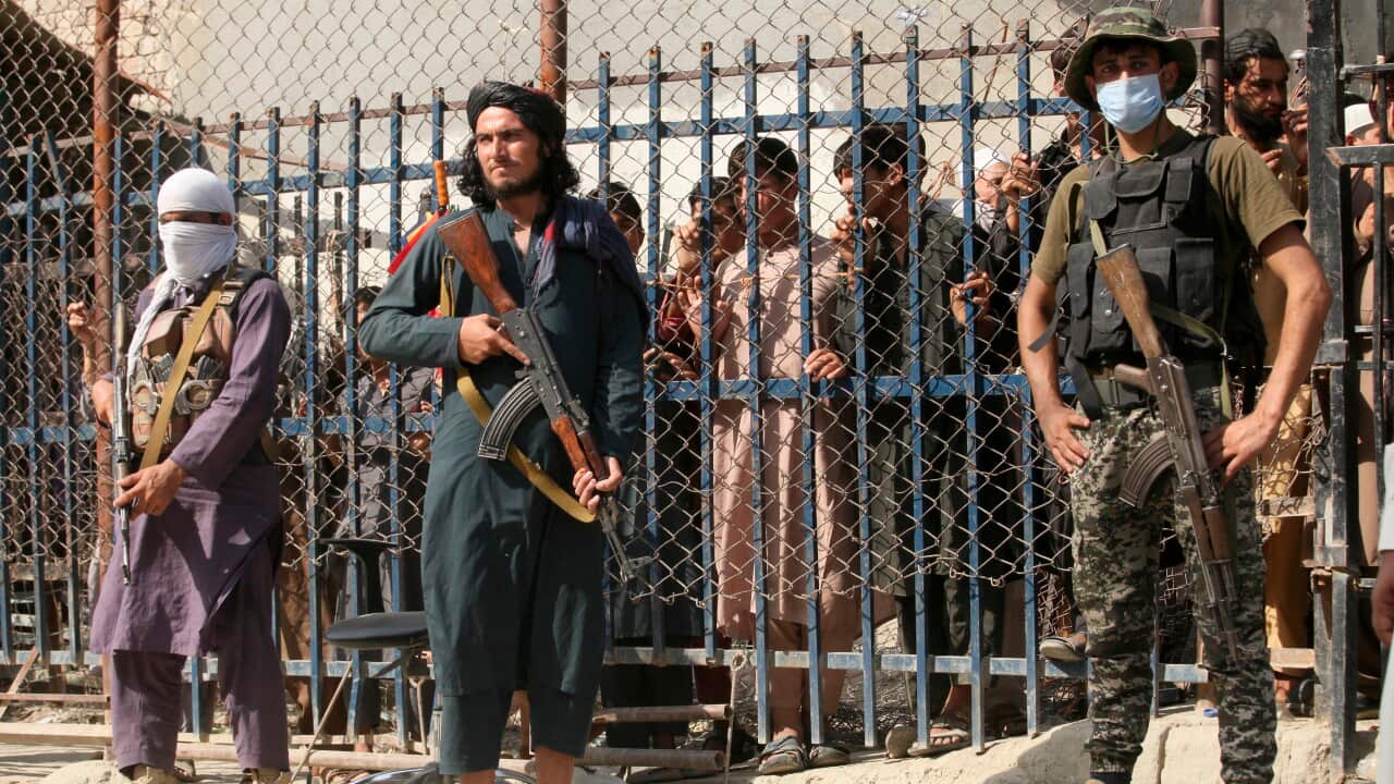 A Pakistani paramilitary soldier, right, and Taliban fighters stand guard at a border crossing point between Pakistan and Afghanistan, in Torkham.
