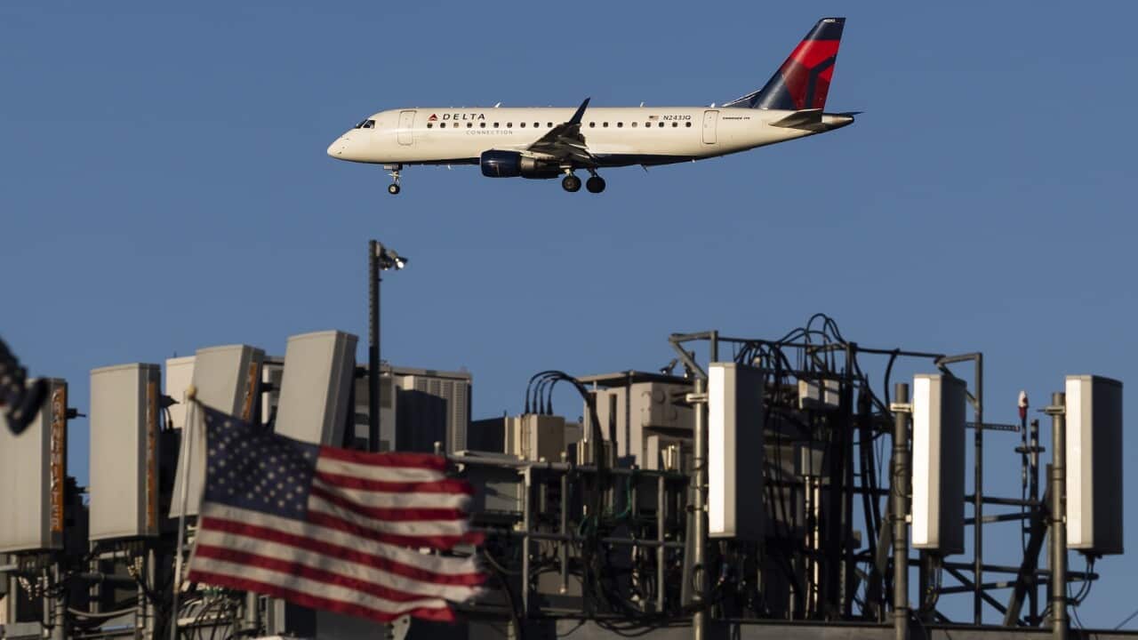 A plane landing in New York passes telecommunications antennae on a rooftop