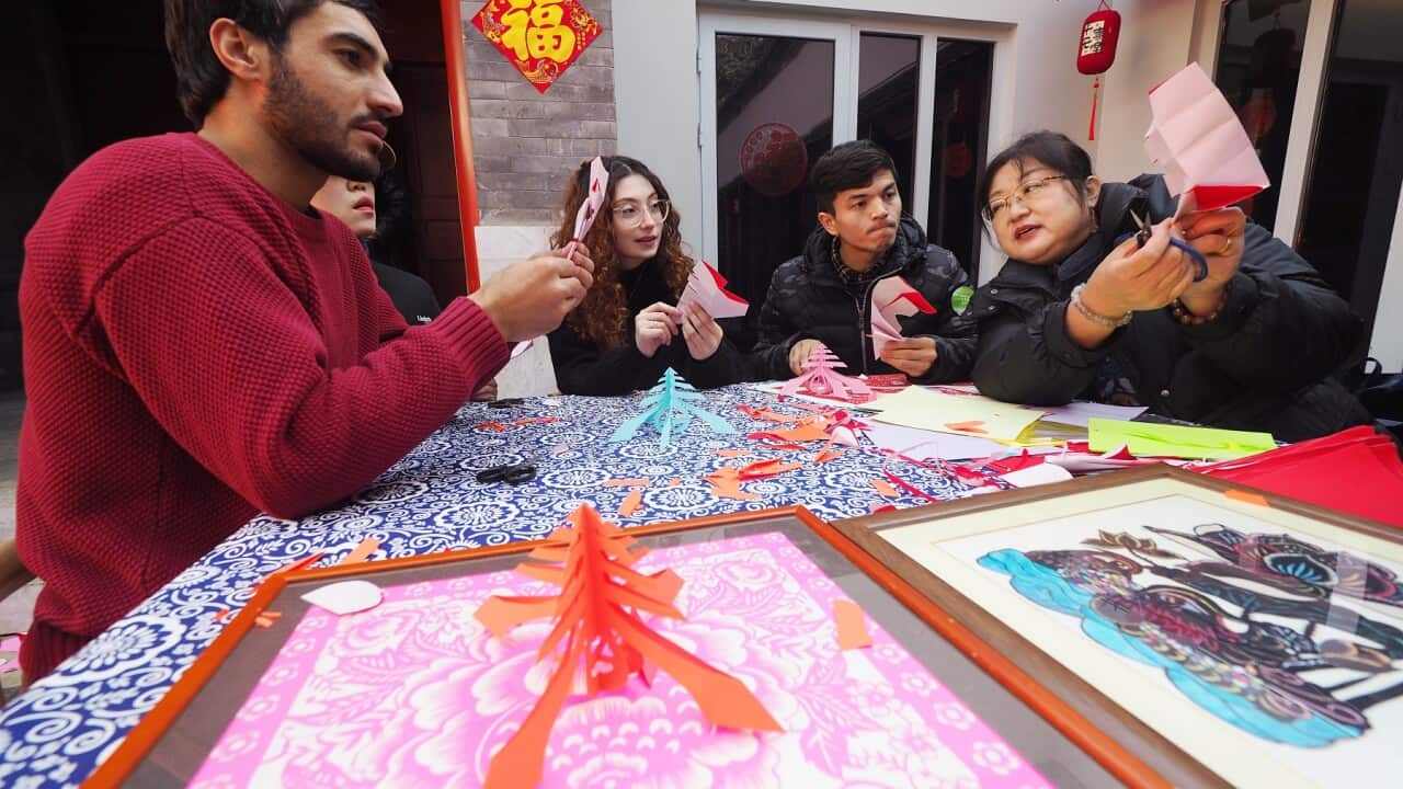 Foreign students experience cutting window cuttings during the warm-up of the Lunar New Year Cultural Temple Fair in Beijing.