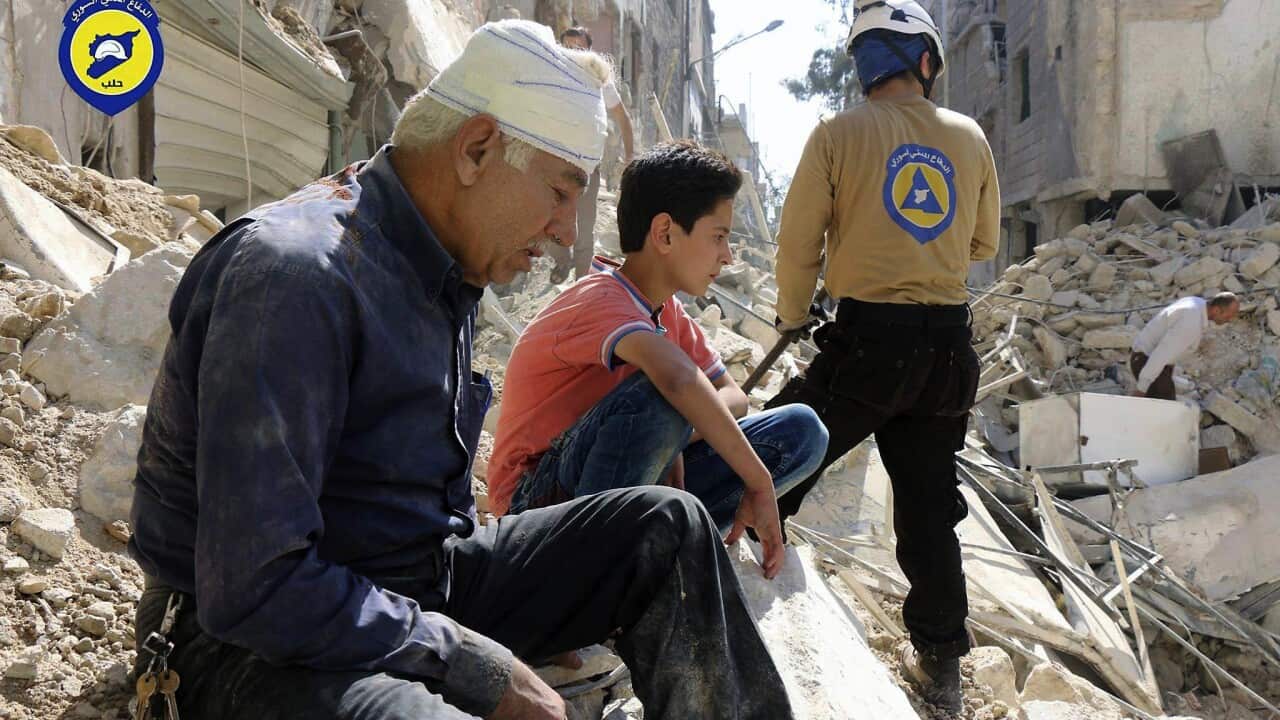 residents sit among rubble in rebel-held eastern Aleppo, Syria.