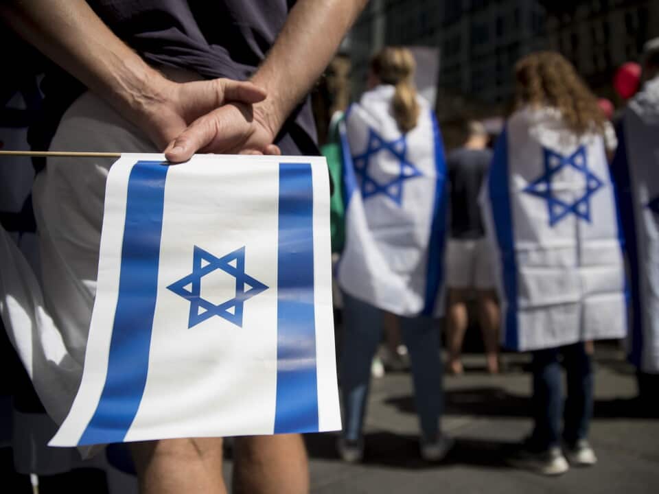 A person holding an Israeli flag behind them and others wearing the flags as capes.