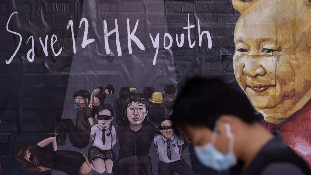 Students walk past a poster supporting 12 Hongkongers who were detained in mainland China. The 12 are accused of illegally crossing the border in a speedboat.