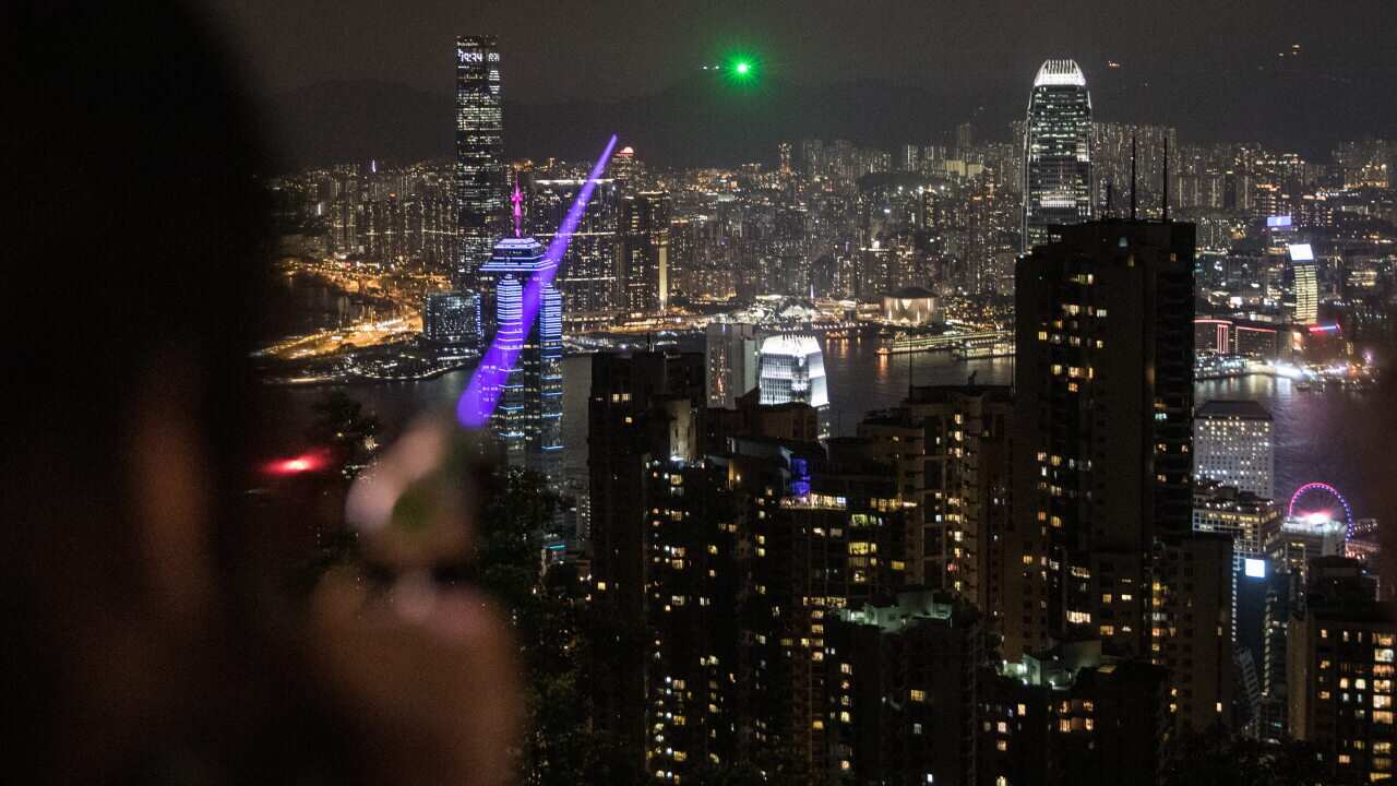 A pro-democracy protester points a high powered laser pointer at other protesters who had gathered on Lion Rock.