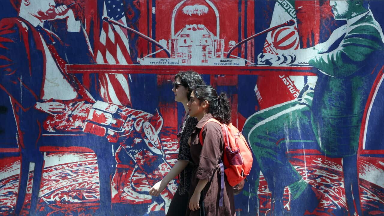 Two girls walk in front of a mural