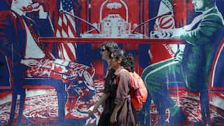 Two girls walk in front of a mural