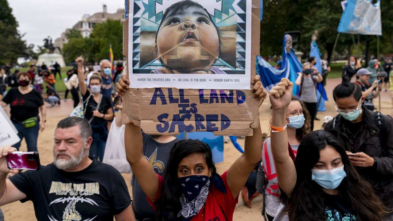 Indigenous and environmental activists protest in front of the White House.