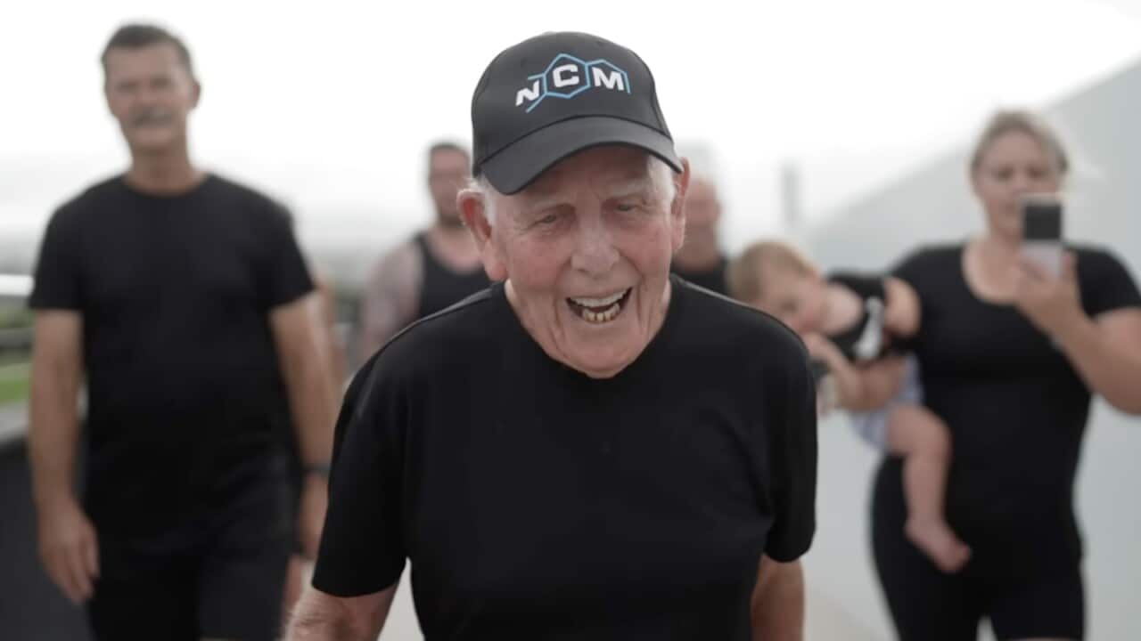 An elderly man in a black shirt and hat running.
