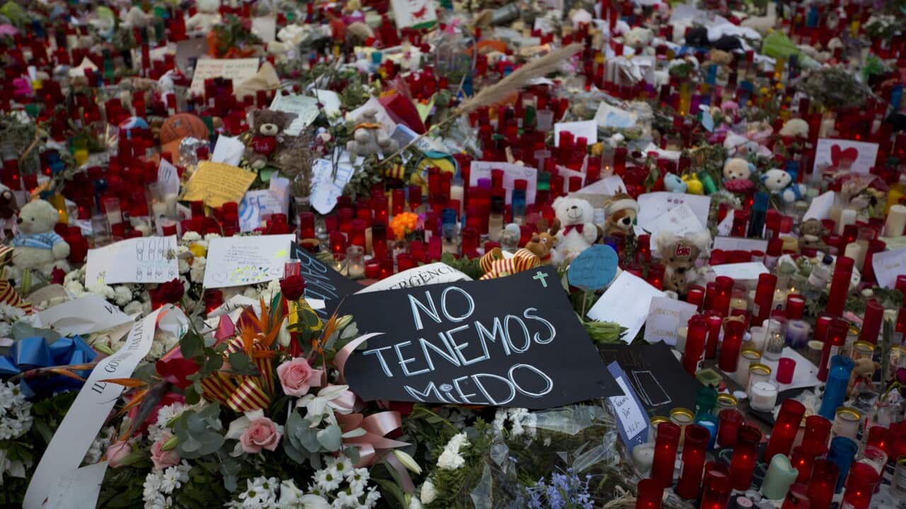 A banner in Spanish reads "we are not afraid", next to flags, flowers, messages and candles on Barcelona's historic Las Ramblas promenade.