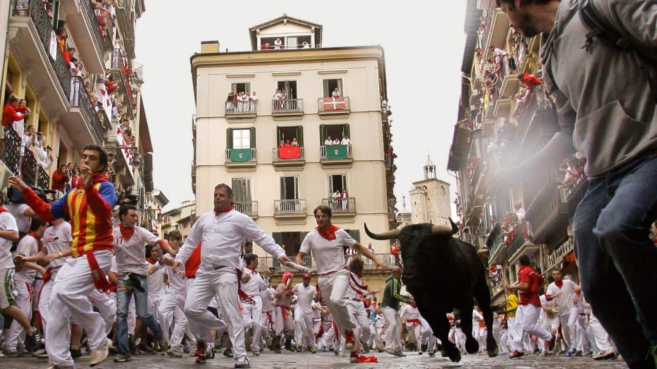 a bull charging down a Spanish street as participants run in front