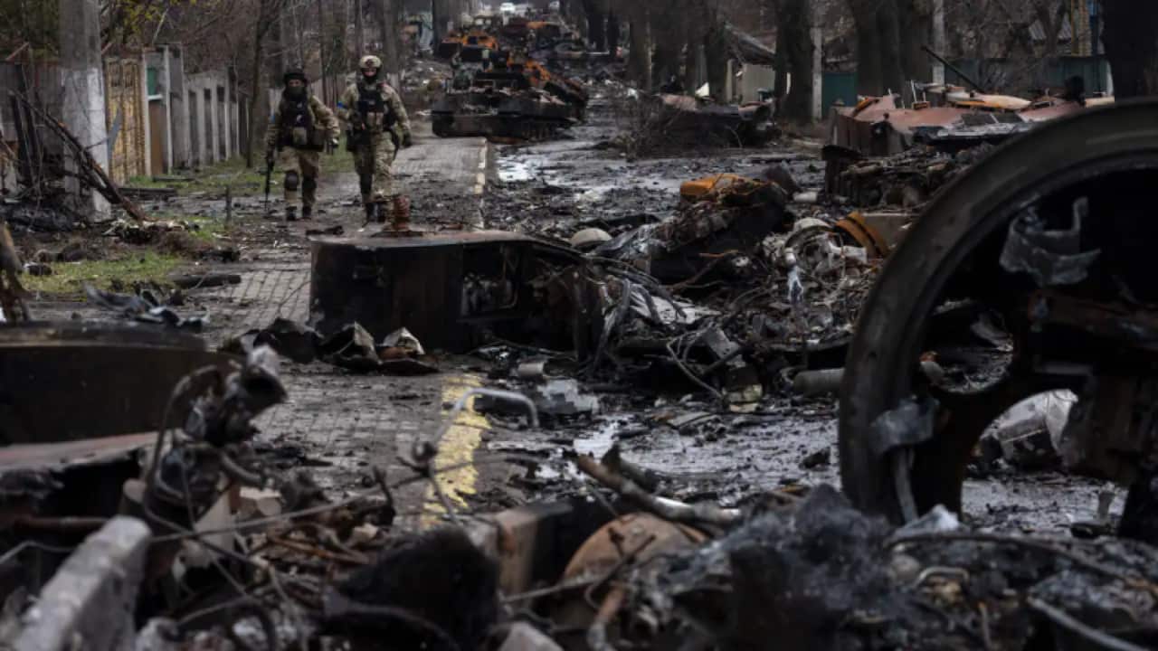 Soldiers walk amid destroyed Russian tanks in Bucha, in the outskirts of Kyiv, Ukraine