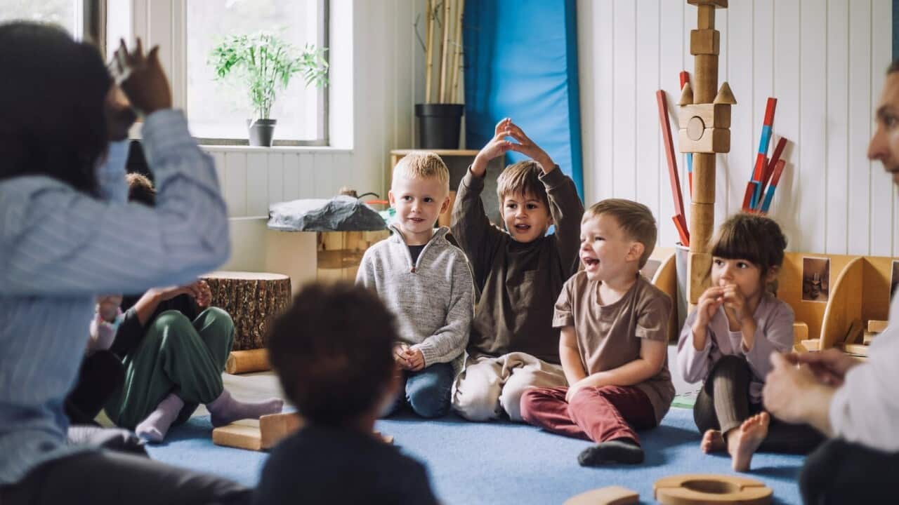 Female child care worker teaching boys and girls in day care center