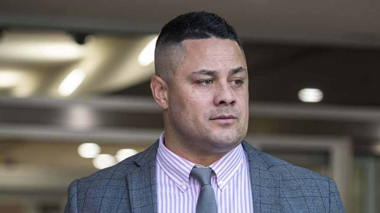 Jarryd Hayne in a suit standing outside a courtroom.
