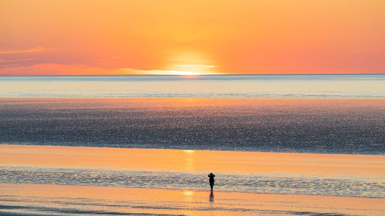 A lday is enjoying the beautiful view at 80 mile beach, in Broome, Western Australia