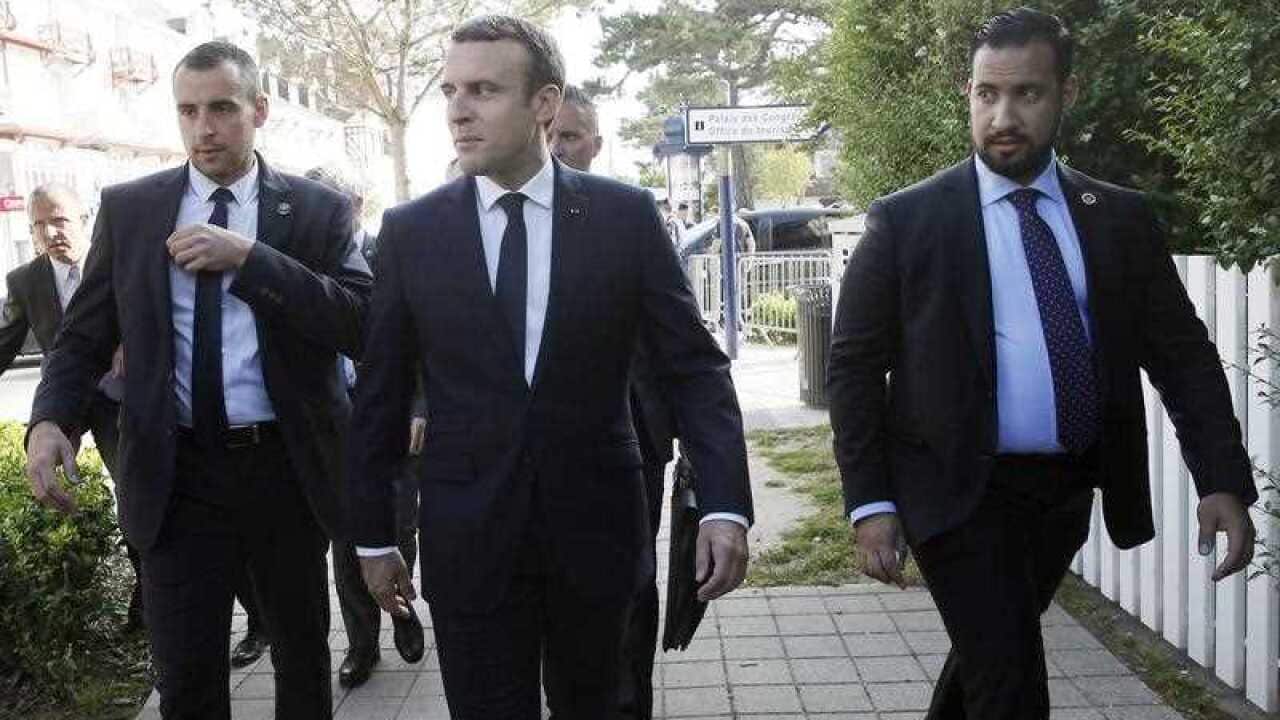 French President Emmanuel Macron (C) flanked by security staff Alexandre Benalla (R) leaves his home.