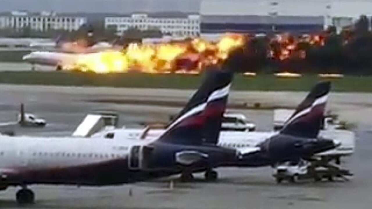 The plane on the Moscow runway with the fire burning at the back