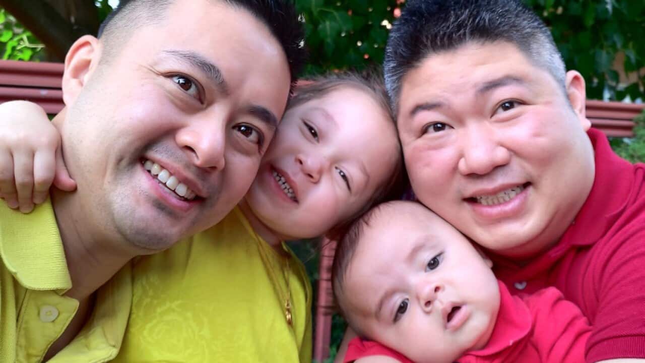 Selfie of two men smiling with two children.