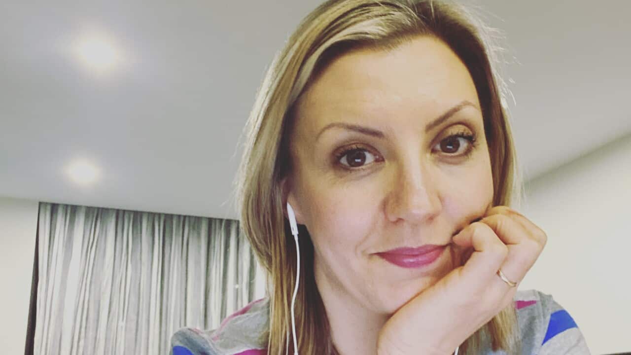 A woman is pictured sitting at a desk, with her hand resting on her chin.