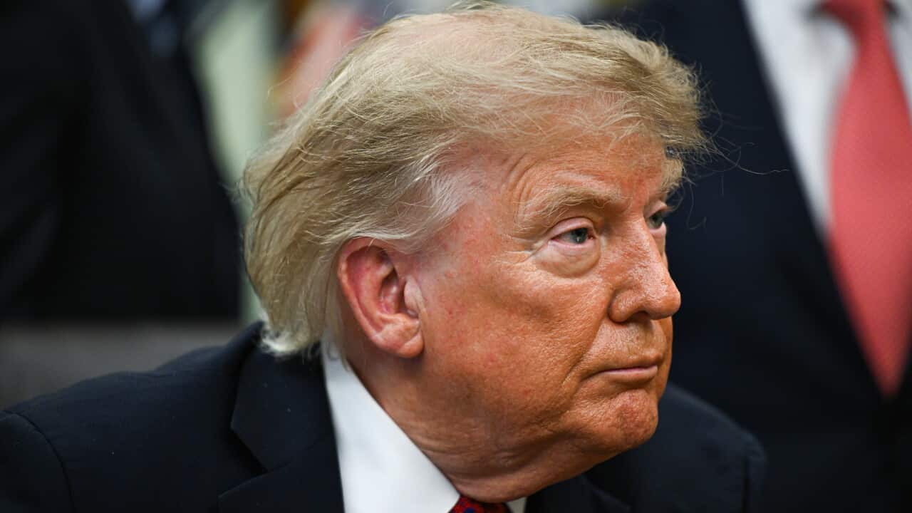 Donald Trump wearing a suit and a red tie.