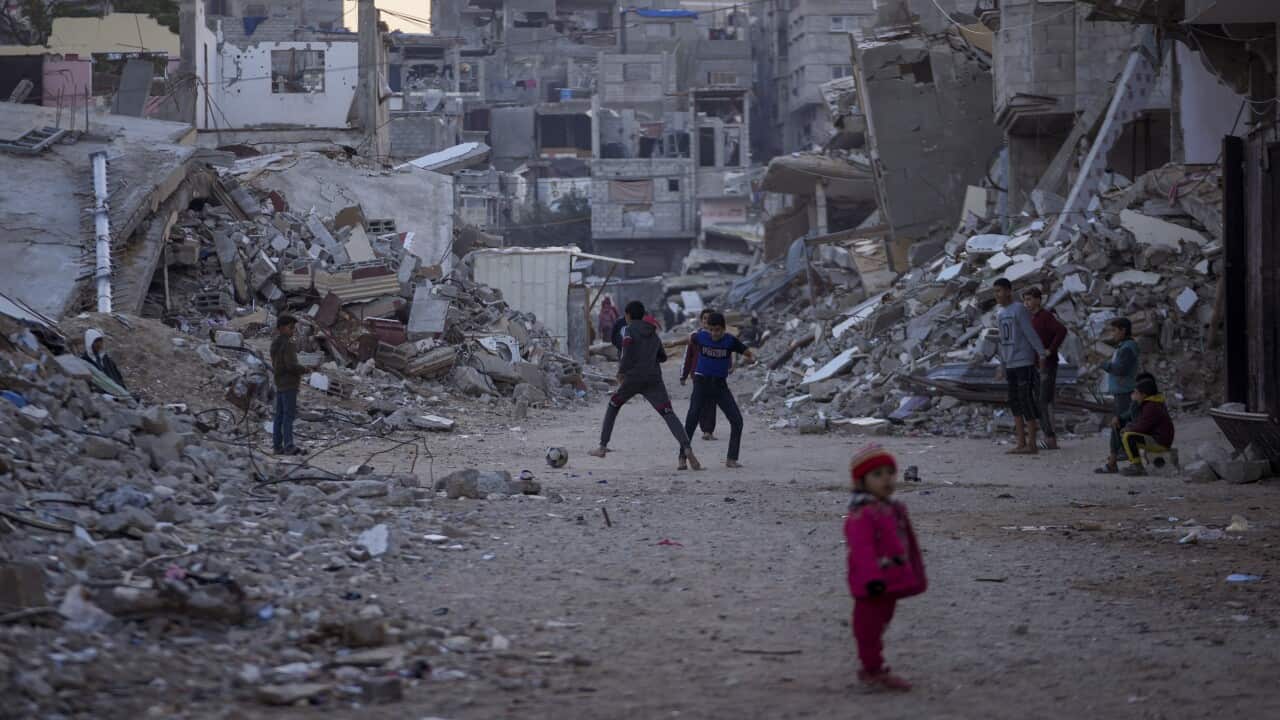 Palestinian children play next to buildings destroyed by Israeli army strikes in Khan Younis, Gaza Strip, Tuesday, Jan. 7, 2025