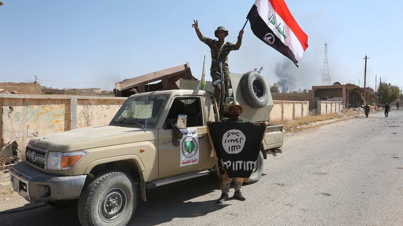 Fighters of Hashed Al-Shaabi (Popular Mobilization units) wave an Iraqi flag and hold another one bearing the logo of IS: Tal Afar