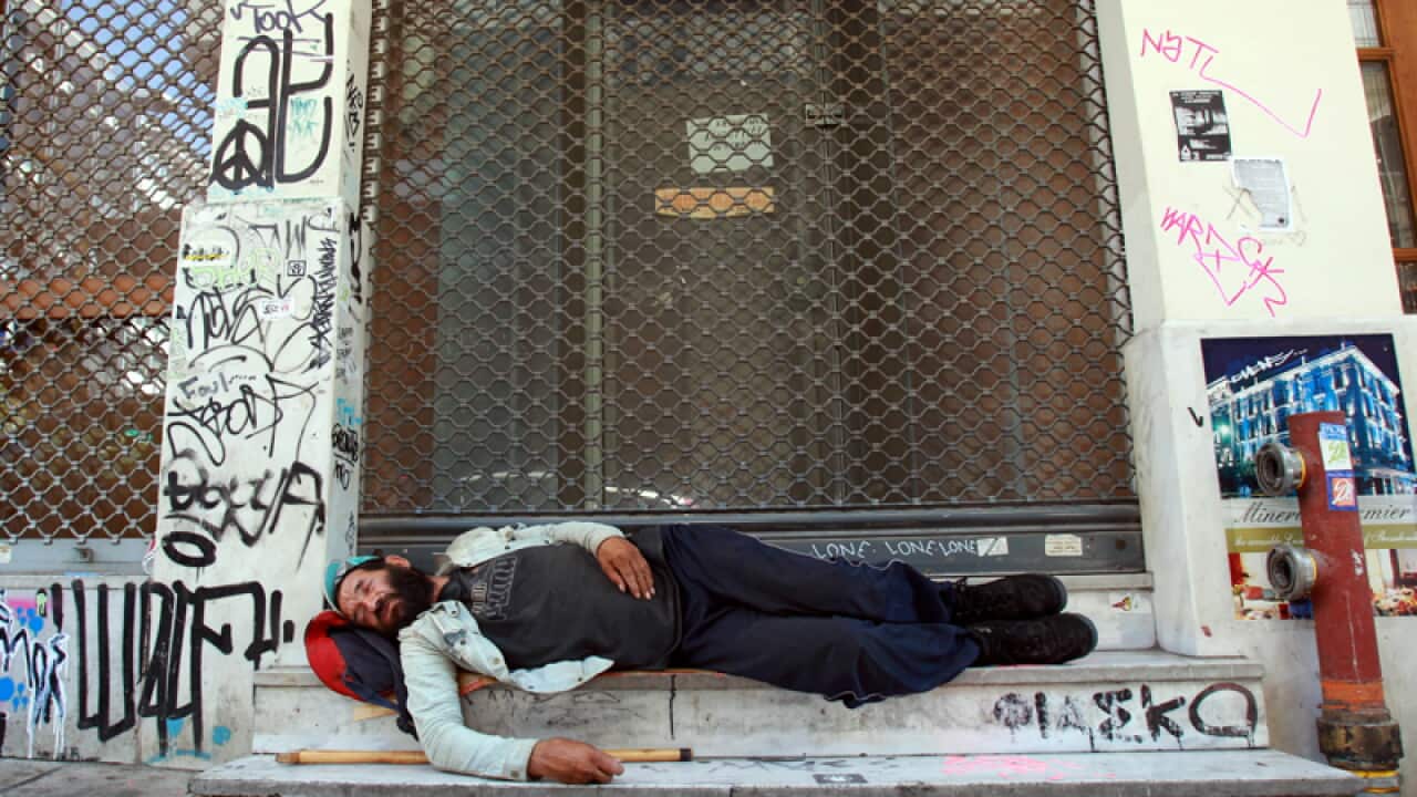 A homeless man sleeps outside a shuttered shops in Thessaloniki
