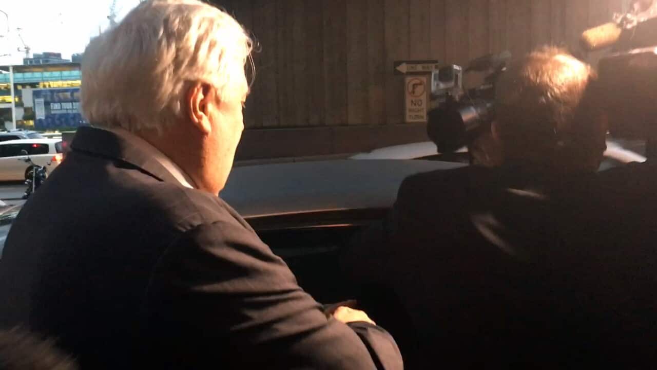 A minder of businessman Clive Palmer gets handsy with members of the media after Palmer left the Federal Court in Brisbane.